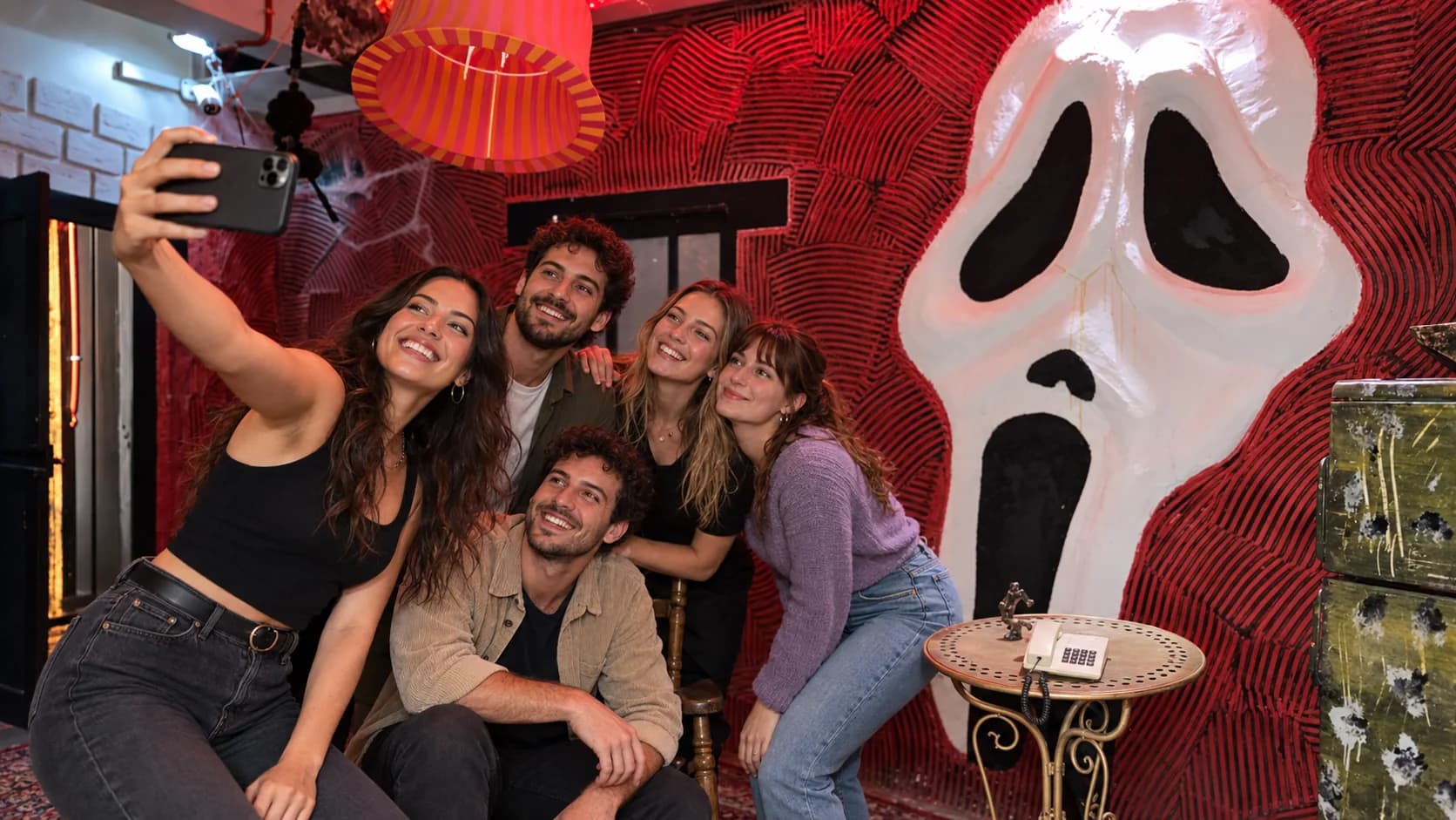 חמישה חברים בדיוניים מצטלמים יחד מול מסכת הצעקה